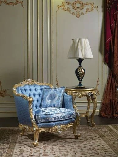 Blue tufted armchair with carved gold trim in a classic interior